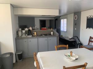 a kitchen with a white table and a table and chairs at La longère de Paul et Suzanne in Pendé