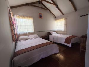 a bedroom with two beds and two windows at Lodge Wayra Wasi in Coporaque