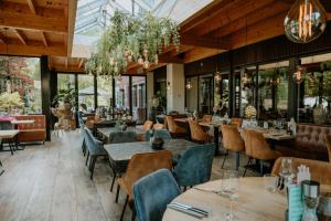 a restaurant with wooden ceilings and tables and chairs at Hotel Jachtlust in Borne