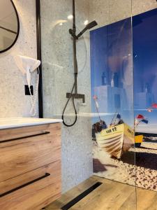 a bathroom with a shower with a boat on the wall at Karwia Marina Apartamenty in Karwia