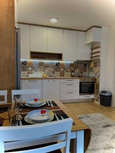 kuchnia z białymi szafkami i stołem z talerzami w obiekcie Apartment Clover Sarajevo w Sarajewie