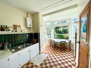 Una cocina con fregadero y una mesa con sillas. en Villa bauloise d'exception plage Benoît, en La Baule