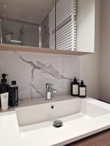 a white sink in a bathroom with bottles on it at Seaview234 in Middelkerke +25 photos