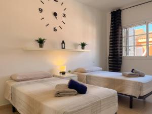two beds in a room with a clock on the wall at Stunning Villa in Meloneras, Maspalomas in Maspalomas