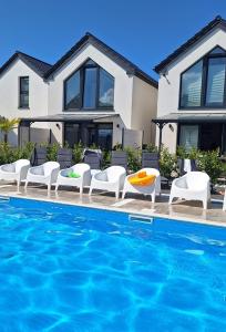 une maison avec une piscine et des chaises blanches et une maison dans l'établissement APARTAMENTY 3 CÓRKI, à Jastrzębia Góra