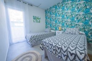 two beds in a room with blue and green wallpaper at GELVESTURIST 2 Free parking in Gelves