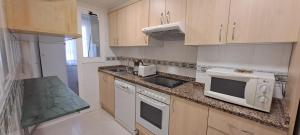 a kitchen with a stove and a sink and a microwave at CARIBE Apartamento in Oropesa del Mar