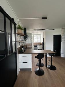 a kitchen with a wooden table and two bar stools at Confort et proximité à Pointe-à-Pitre, logement spacieux pour 4-6 personnes in Pointe-à-Pitre