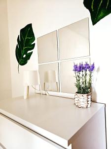 Un escritorio blanco con flores moradas y un espejo. en City-Apartment, en Sinsheim