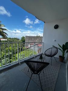 a balcony with a table and chairs and a view at Confort et proximité à Pointe-à-Pitre, logement spacieux pour 4-6 personnes in Pointe-à-Pitre