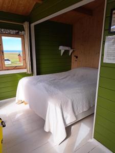 a bed in a green room with a window at Guesthouse Hof in Hofgarðar +66 photos