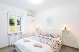 a white bedroom with a bed and a window at Borea Strunjan in Portorož