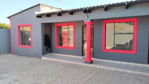 a building with red windows on the side of it at Rasesa Guesthouse Block V in Soshanguve