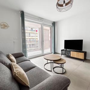 a living room with a couch and a tv at Lumineux, terrasse cosy et parking privé inclus in Metz