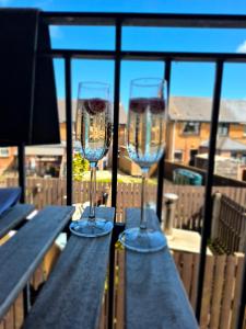 two wine glasses sitting on a table on a balcony at Tailte Trá in Carnlough