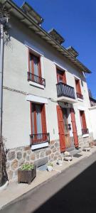 a white building with red shutters on a street at Villa Mon Repos 3 in La Bourboule