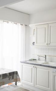 a white kitchen with a sink and a window at Appartement 2 pièces Cavalaire sur Mer 60m2 in Cavalaire-sur-Mer