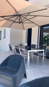 una sala da pranzo con tavolo e sedie bianchi di Villa mitoyenne de standing proche de toutes commodités à Ghisonaccia a Ghisonaccia