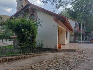 a small white house with a gate and a fence at Cabaña la candela in Bernal