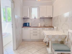 a kitchen with white cabinets and a table with a microwave at Rosemary Apartment in Promajna +38 photos