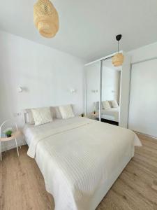 ein weißes Schlafzimmer mit einem großen Bett und einem Spiegel in der Unterkunft Haustory Palanga Apartment in Palanga