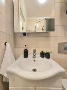 ein Badezimmer mit einem weißen Waschbecken und einem Spiegel in der Unterkunft Haustory Palanga Apartment in Palanga + 18 Fotos