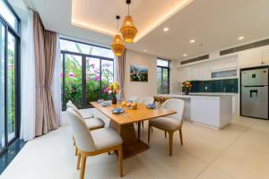 a kitchen and dining room with a wooden table and chairs at Ocean sand villa in Cam Lâm
