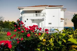 a white building with red flowers in front of it at Villa Mae in Elaiokhórion
