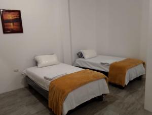 two beds in a room with white walls at Casa Almendro in Puerto Villamil