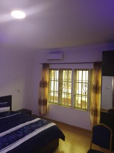 a bedroom with a bed and two windows at Peace Home in Lekki