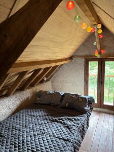 L ancien fournil - Sejour authentique & douillet - Proche de Sarlat في Calviac: سرير في غرفة ذات سقف خشبي ونوافذ