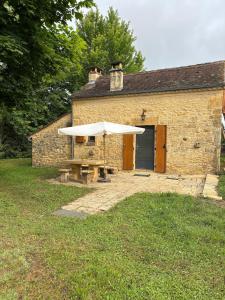 L ancien fournil - Sejour authentique & douillet - Proche de Sarlat في Calviac: مبنى به طاولة نزهة ومظلة +15 صورة