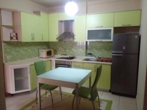 a kitchen with green cabinets and a table and a refrigerator at Ofellows - Kristal Center in Tirana