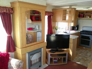 un salon avec une télévision et une cheminée dans l'établissement Golden Palm Mirage GP 6 Berth enclosed veranda, à Chapel St. Leonards