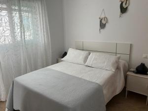 sypialnia z białym łóżkiem i oknem w obiekcie APARTAMENTO CALMA EN EL CENTRO w mieście Conil de la Frontera