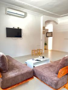 a living room with two couches and a tv at Apartment in town, 5 min walk to beach access in Saidia 