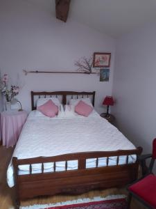 a bedroom with a large bed with pink pillows at Gîte de baigneux 2 étoiles in Moncontour-de-Poitou +6 photos