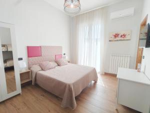 a white bedroom with a bed with a pink headboard at AlbaNova in Naples
