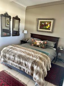 1 dormitorio con 1 cama con manta y 2 espejos en Die Wit Haas, en Nieuwoudtville