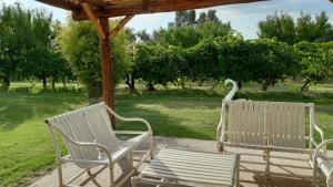 two white chairs and a bench under a gazebo at Finca Don Juan Piedra Alta in Junín