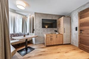 una camera con tavolo e TV a parete di Hotel Berghof Mayrhofen GmbH a Mayrhofen