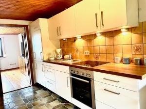 a kitchen with white cabinets and a sink and a stove at Ferienwohnung Bayerischer Wald in Zwiesel