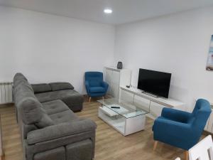 a living room with a couch and two chairs and a television at Los fresnos de ribadesella 4 personas in Ribadesella