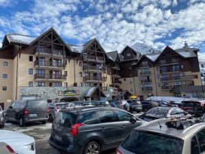 un parking avec des voitures garées devant un bâtiment dans l'établissement Résidence Les Hauts de Valmeinier 1900, à Valmeinier