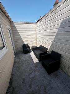 un patio con due divani seduti accanto a un muro di Maison proche de toutes commodités a Dunkerque