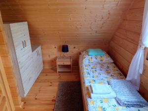 a small room with a bed in a wooden cabin at Domki u Asi in Wilkasy
