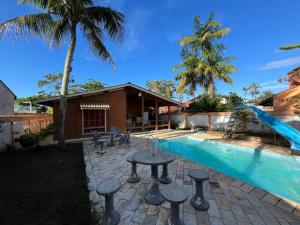 una piscina con un tavolo e uno scivolo accanto a una casa di Casa Tranquila com piscina pra família e grupos c a Bertioga