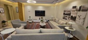 a living room with a couch and chairs and a tv at The Zamalek Residence in Banī Ghālib