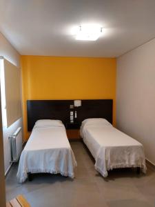 two beds in a room with yellow walls at Departamentos Rada in Rada Tilly