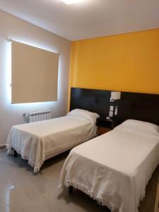 two beds in a room with yellow walls at Departamentos Rada in Rada Tilly